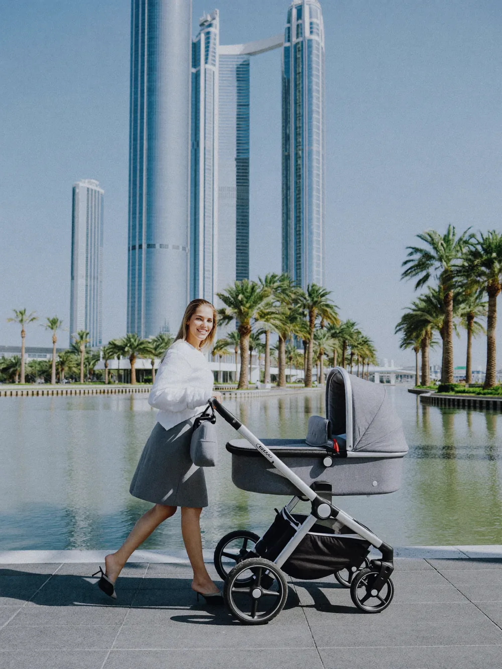 Woman pushing a baby stroller along a Dubai promenade