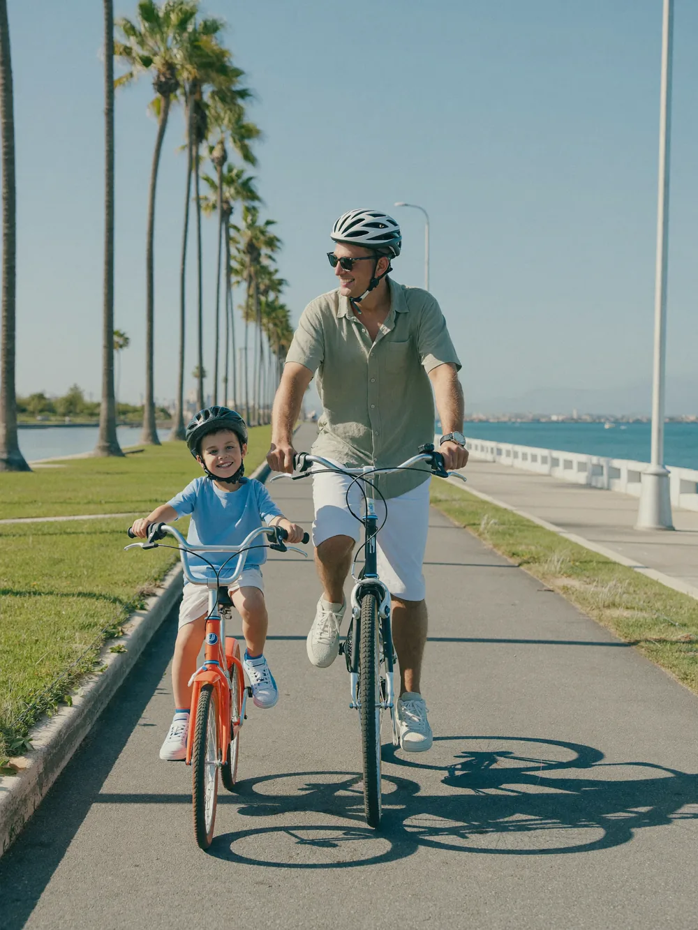 Father and son cycling on a sunny waterfront path